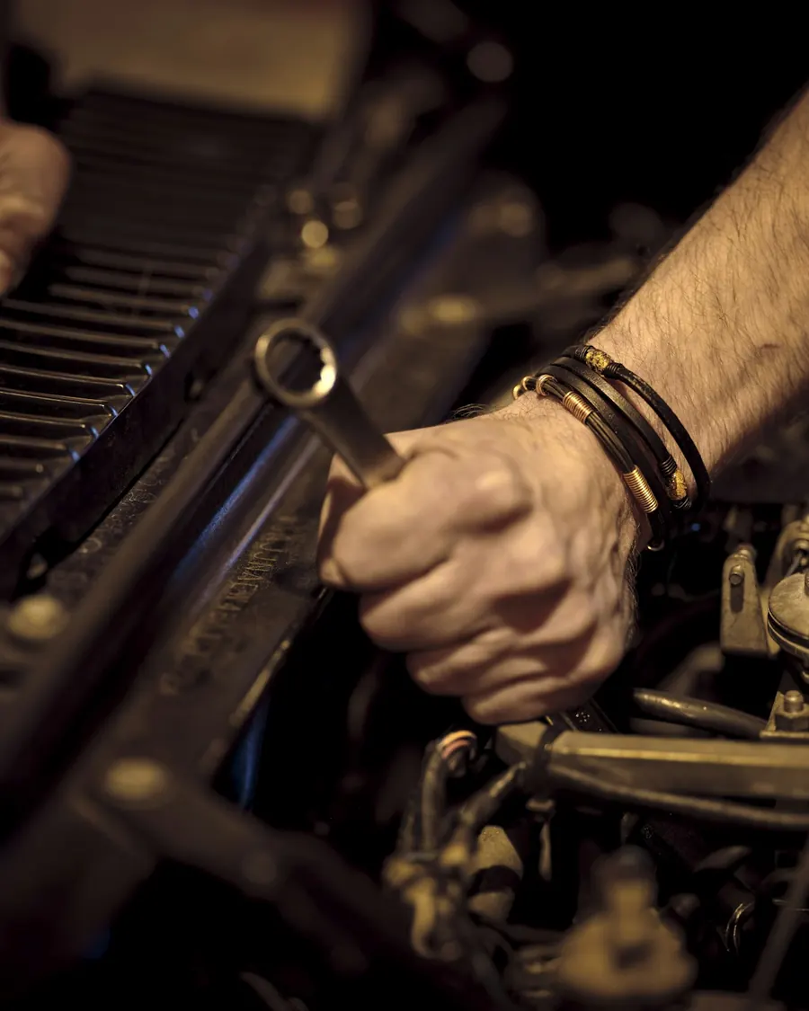 A mechanic's hand turning a wrench in an engine bay